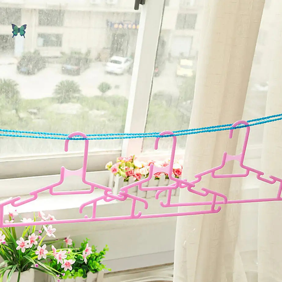 Pink plastic hangers securely spaced on a blue fence-style clothesline mounted near an indoor window, perfect for apartments in Pakistan.